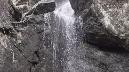 Wasser fällt von einem mittelgroßen Wasserfall mit dunkelbraunen Felsen\_slomo