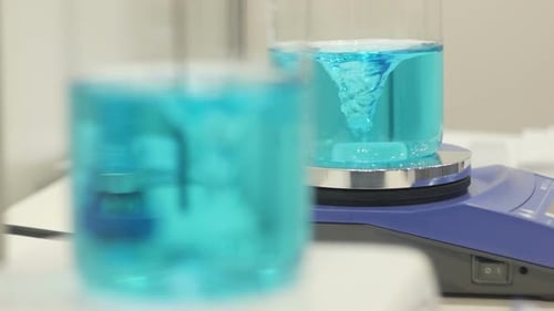 Blue Liquid Swirling in Beakers on Magnetic Stirrers