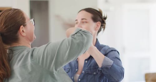 Two Women Holding Hands Dancing Together Indoors
