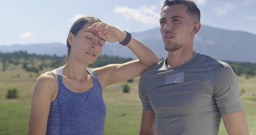 Athletic Couple Cooling Down in a Mountain Field