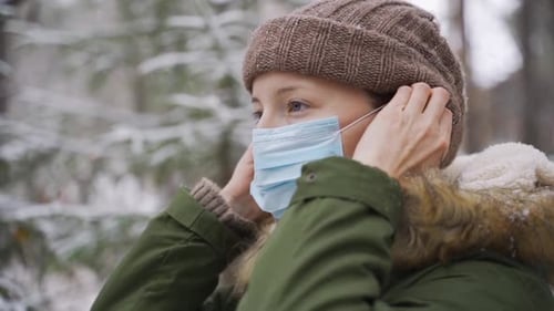 Young Woman Putting on a Medical Mask To Prevent the Virus Spread During the Walking in the Park