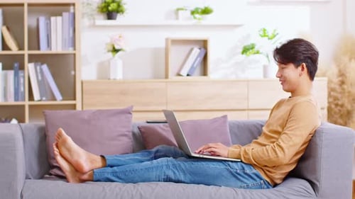 Young Adult Relaxing on Couch with Laptop