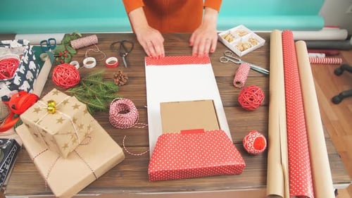 Woman Wrapping Christmas Presents on a Wooden Table