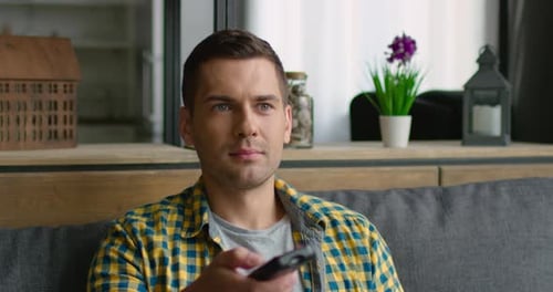 Man Changing Channels on TV at Home