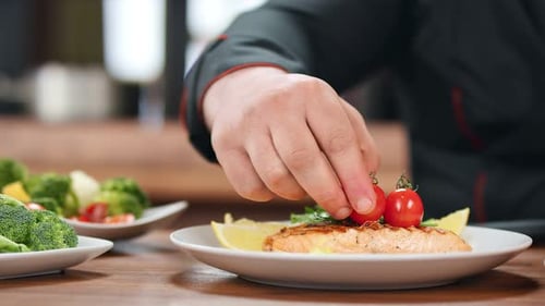 Chef Garnishing Salmon Plate with Tomatoes in Restaurant