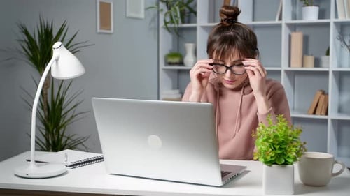 Müde junge Frau arbeitet zu Hause am Laptop