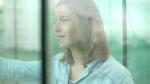 Woman looking through window with dreamy expression on face