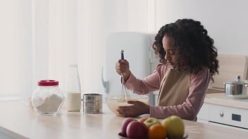Girl Smiles Whisking Dough in Kitchen