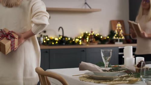 Women Exchanging Christmas Gifts in Decorated Kitchen