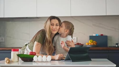 Child Kisses Woman in Kitchen