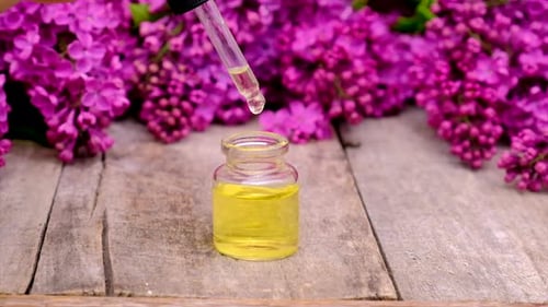 Dropping Essential Oil into Bottle with Lilac Flowers