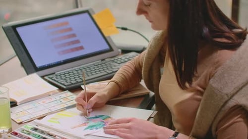 Woman Creates Watercolor Painting in Indoor Setting