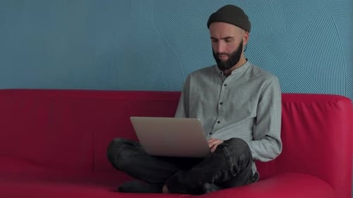 Young Adult Working on Laptop on Couch Indoors