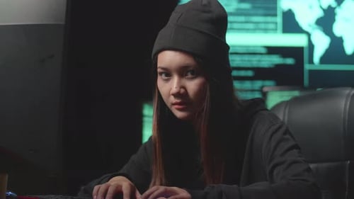 Young Adult Hacker Typing Code in a Dark Room