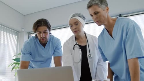Medical Team Reviews Laptop in Bright Office