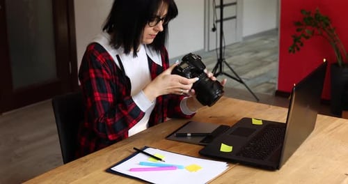 Photographer Female Working in a Creative Office Holding Camera at Desk and Retouch Photo