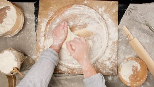 two female hands knead dough from white wheat flour on a wooden board