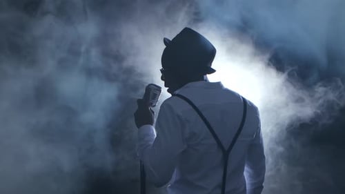 Man Singer the View From the Back in the Smoke and White Light Sings Into a Microphone and Dance