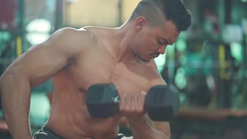 Asian attractive young sportsman trainer workout, exercise lifting weight dumbbell in gym stadium.
