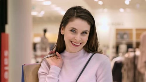 Smiling woman with full shopping bags in shopping mall