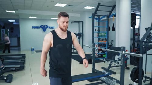 Athletic man starts his daily workout with female trainer in gym