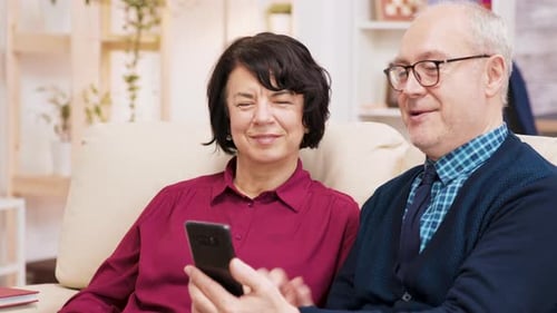 Senior Couple Using Phone for Video Call at Home