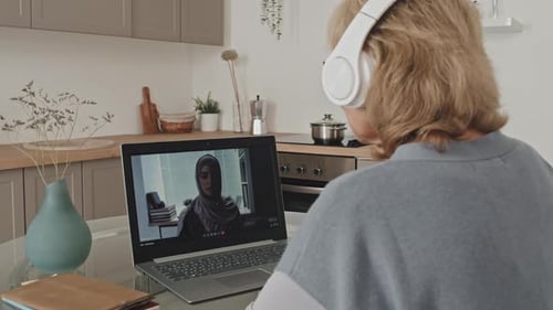 Une femme âgée parle avec une collègue lors d'un appel vidéo depuis la maison