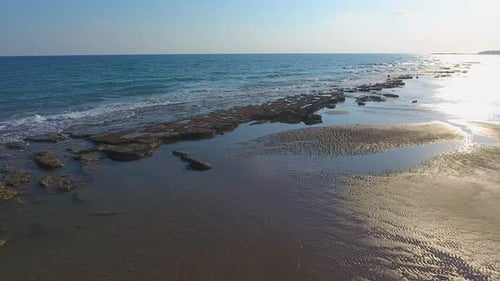 Flaches Felsenriff zwischen Meer und Strand