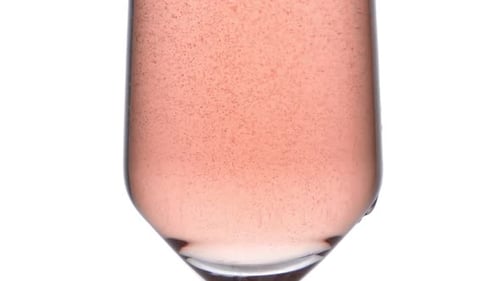 Primer plano de una copa con confeti de estrellas doradas decorada con vino rosado espumoso, fiesta de celebración