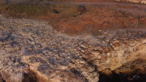 Drone top down aerial view of waves splash against rocky seashore, background. Flight over high clif