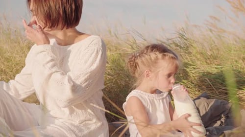 Mother with Children Lunch on Nature with Bread and Milk