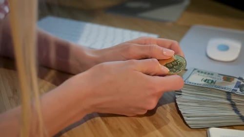 Female Hands Holding Bitcoin. Crop View of Hands of Woman Holding Shiny Metal Bitcoin Sitting at