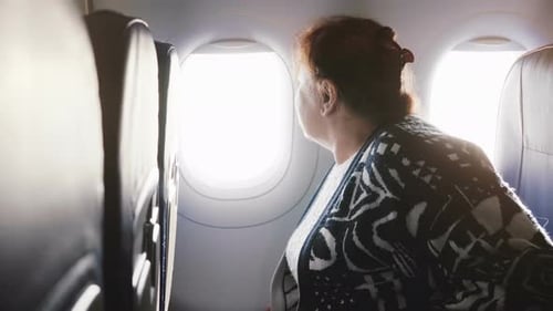 Senior Woman Looking out Airplane Window on Flight