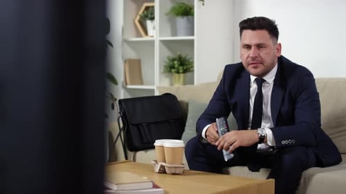 Man in Suit Watching TV with Frustration