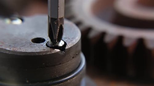 Screwdriver Tightens Screw on Metal Gear