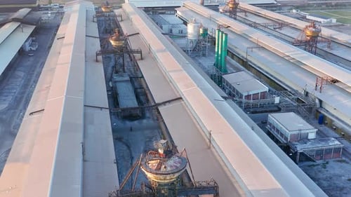 Long industrial halls in a metal factory with smokestacks, towers and heavy equipment