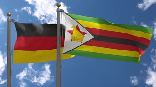 Germany and Zimbabwe Flags Waving Against Blue Sky