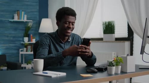 Young Adult Using Mobile Phone at Desk Indoors