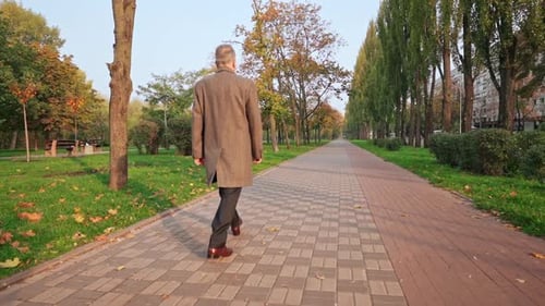 Man Walking in Autumn Urban Park