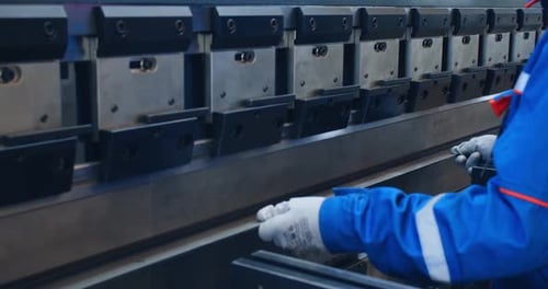 Arbeiter benutzt eine große Industriepresse auf einem Stück Metall,