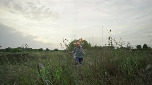 Boy Running Through Field with Toy Airplane