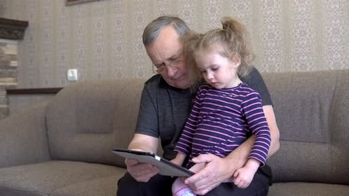 Child and Adult Looking at a Tablet
