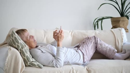 Senior Woman Relaxing with Cellphone on Couch
