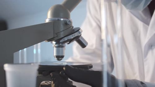 Closeup of a Man in a Laboratory Setting Up a Microscope Over a Glass Slide