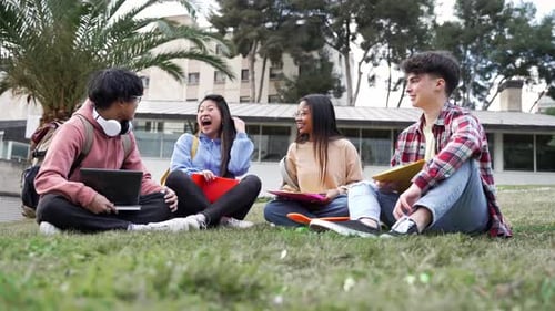 Amigos de estudantes universitários sentados na grama conversando e compartilhando momentos no campus da faculdade