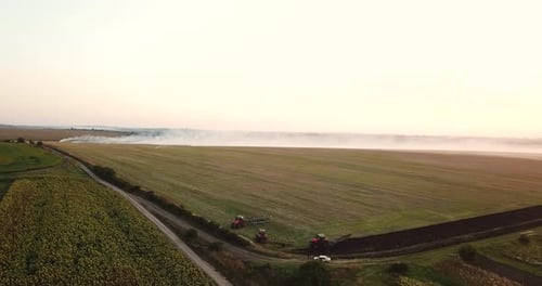 Tractors Plowing Field at Sunrise Aerial View