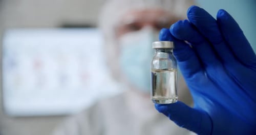 Blured Doctor's Hand Holds Ampoule Vaccine Bottle at the Hospital