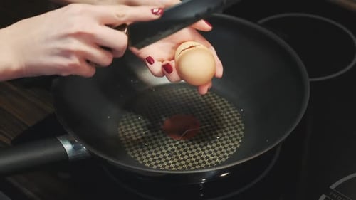 Hands Cracking Egg into Wok on Stovetop