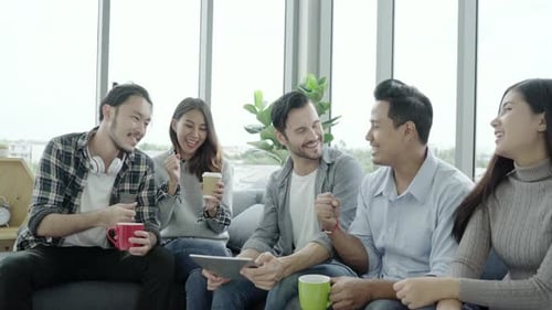 People group team holding coffee cups and discussing ideas meeting with tablet sitting on couch