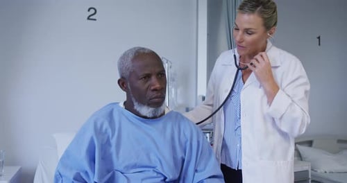 Caucasian female doctor examining african american senior male patient with stethoscope at hospital